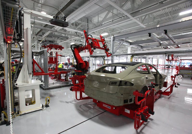 特斯拉弗里蒙特工厂产线上，红色工业机器人为 Model S 白车身安装玻璃车顶